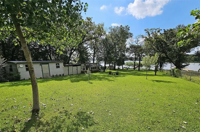 a view of a house with a big yard and potted plants and large trees