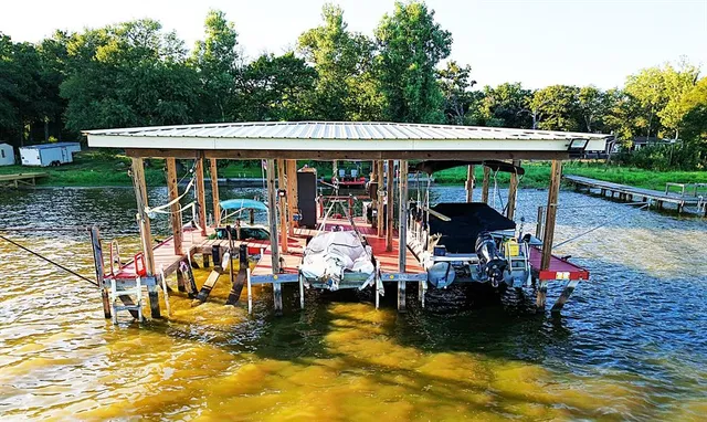 a view of a patio with table and chairs a barbeque with wooden floor and roof with a view of roof with sitting area