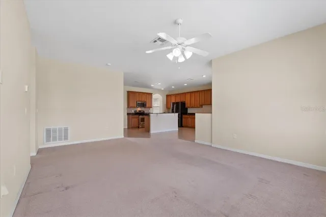 an empty room with kitchen view and windows