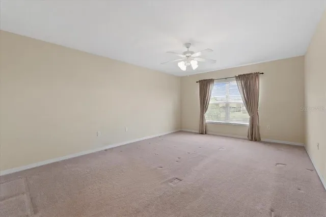an empty room with a ceiling fan and window