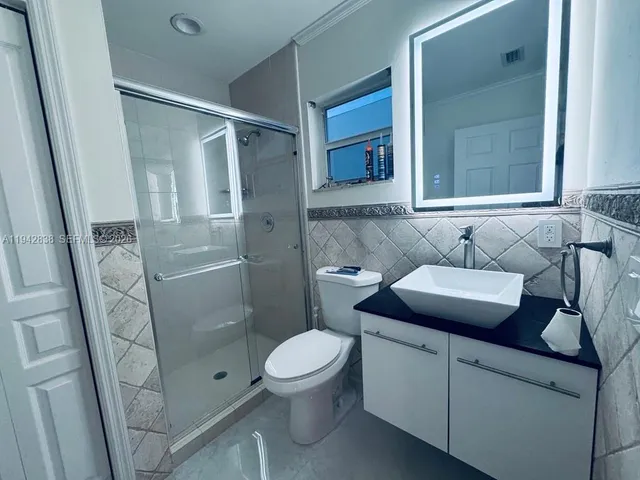 a bathroom with a granite countertop sink toilet and shower