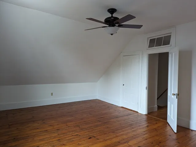 a view of a room with wooden floor and a ceiling fan