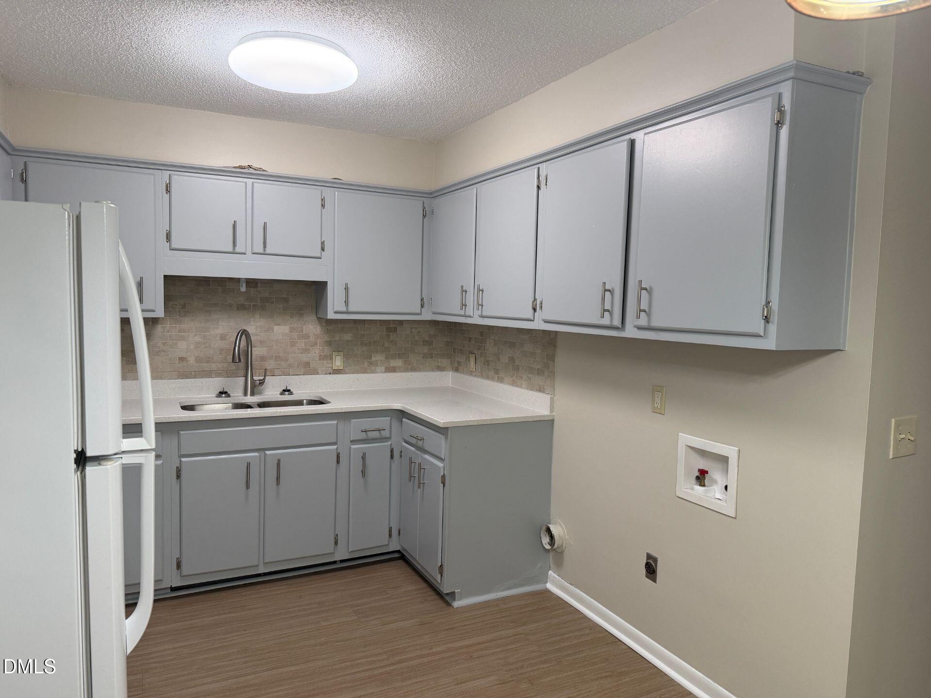 205 East Ransom Street, Unit 1B Fuquay-Varina, NC 27526 - Photo 7 of 8 a kitchen with stainless steel appliances granite countertop a sink and a refrigerator