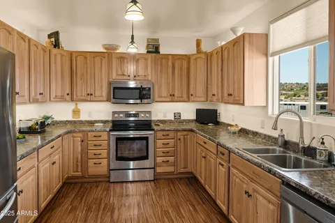 a kitchen with stainless steel appliances granite countertop a stove a sink dishwasher and a microwave oven with wooden floor