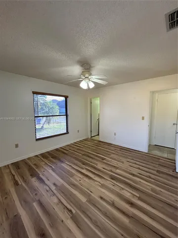 a view of a room with wooden floor and chandelier fan