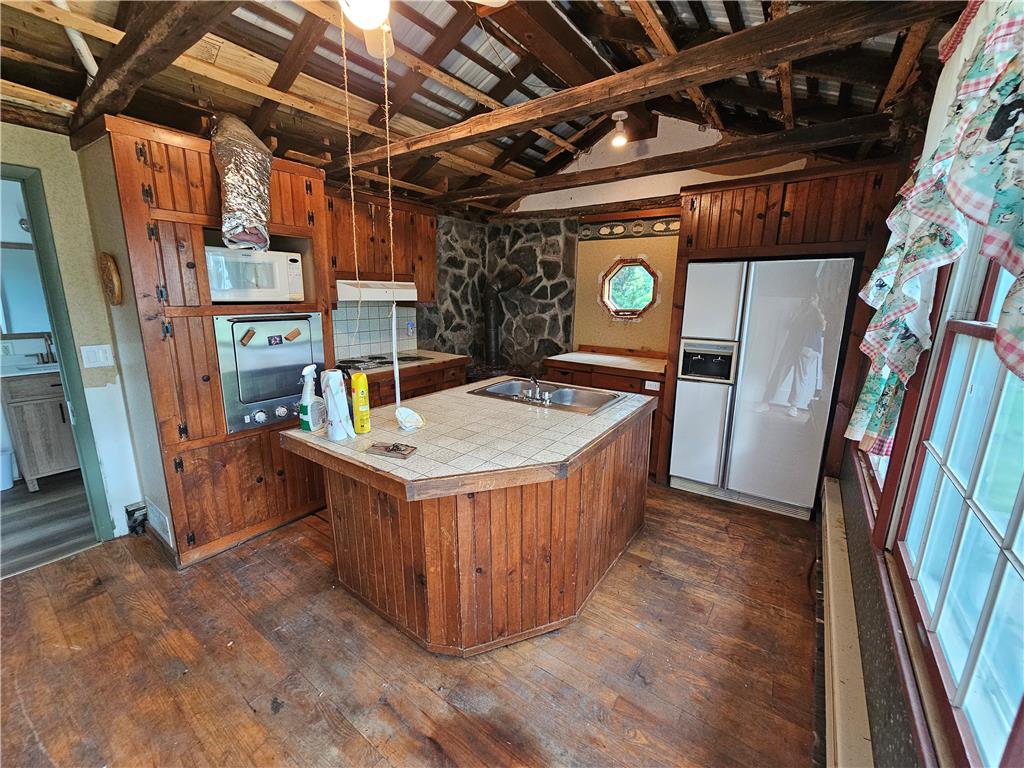 9128 Slateville Road Kempton, PA 19529 - Photo 7 of 13 A rustic kitchen space features a practical island, warm wood cabinetry, and exposed ceiling beams.