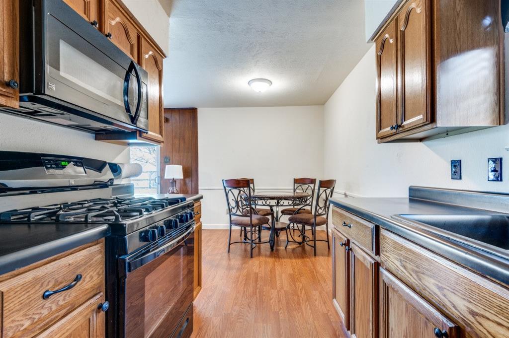 2413 Cheyenne Street Irving, TX 75062 - Photo 11 of 19 a kitchen with stainless steel appliances granite countertop a stove top oven a sink dishwasher a dining table and chairs with wooden floor