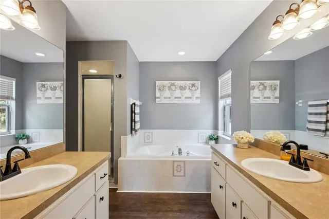 a bathroom with a sink double vanity granite tub shower and a mirror