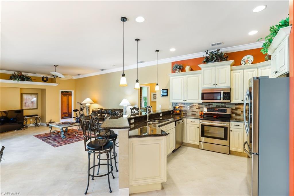 8906 Lely Island Circle Naples, FL 34113 - Photo 11 of 34 a kitchen with stainless steel appliances kitchen island granite countertop a stove and white cabinets