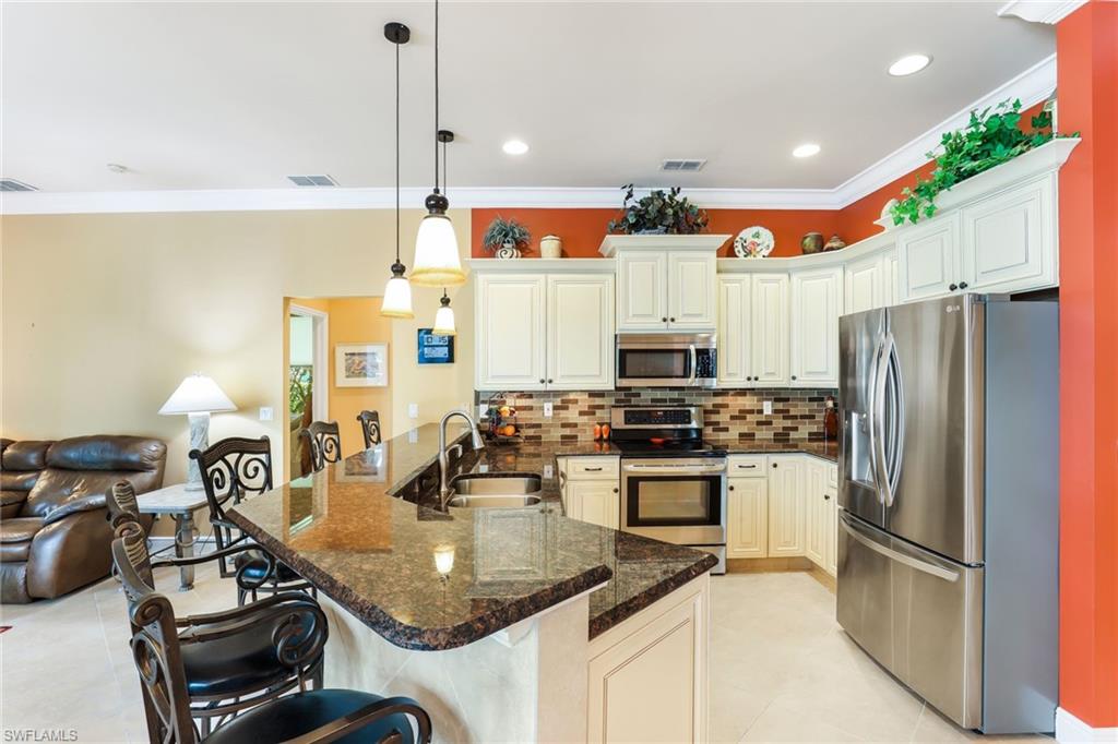8906 Lely Island Circle Naples, FL 34113 - Photo 12 of 34 a kitchen with kitchen island granite countertop a sink appliances and cabinets