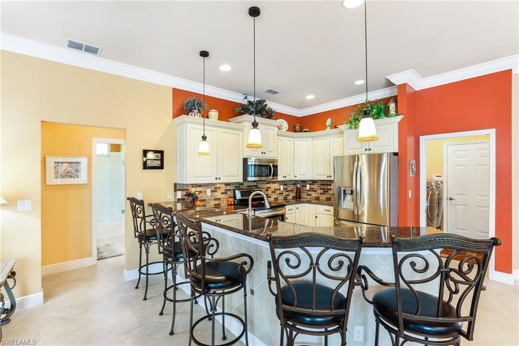 8906 Lely Island Circle Naples, FL 34113 - Photo 13 of 34 a kitchen with stainless steel appliances a table and chairs in it