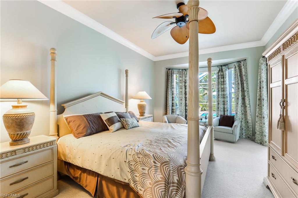8906 Lely Island Circle Naples, FL 34113 - Photo 20 of 34 a bedroom with a large bed and a chandelier