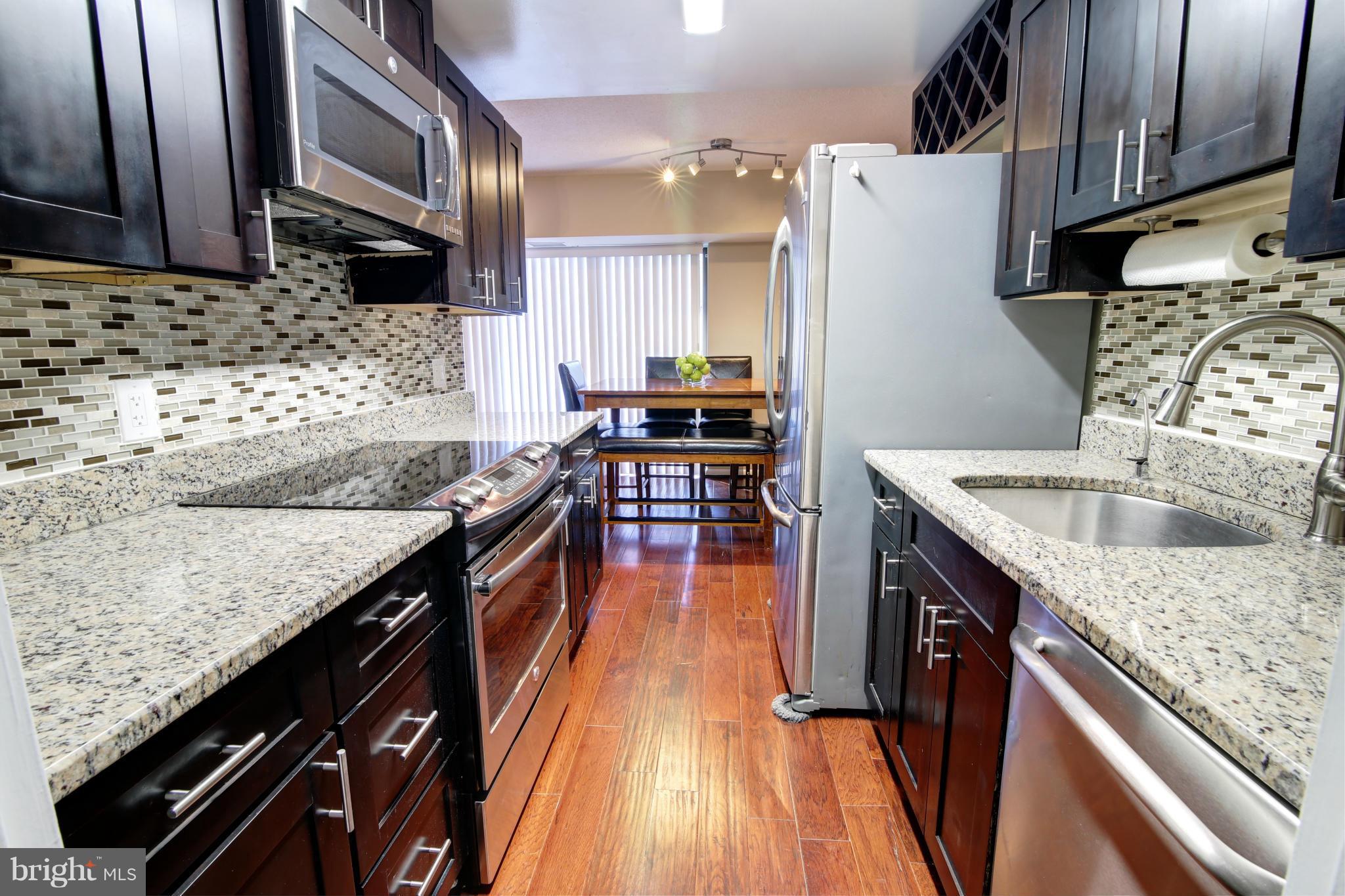 11627 Stoneview Square, Unit 11C Reston, VA 20191 - Photo 1 of 19 a kitchen with granite countertop a sink a counter top space stainless steel appliances and cabinets