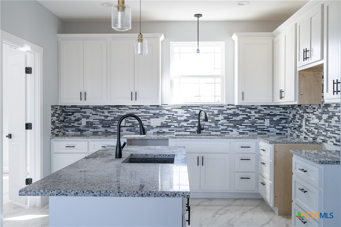 1000 Black Ankle Road Lockhart, TX 78644 - Photo 22 of 40 a kitchen with granite countertop a sink a window and stainless steel appliances