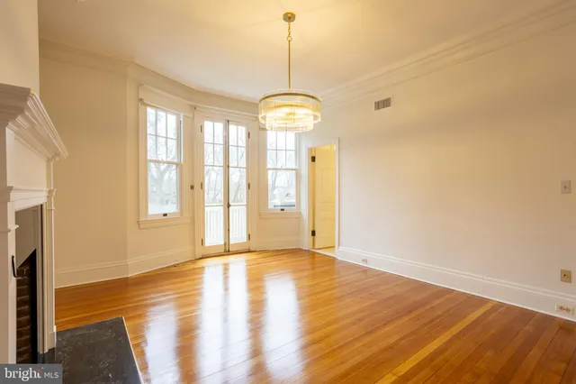 a view of an empty room with window and wooden floor