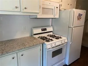 a kitchen with granite countertop cabinets and white appliances