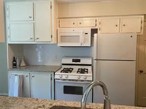 a kitchen with stainless steel appliances granite countertop a refrigerator sink stove and white cabinets