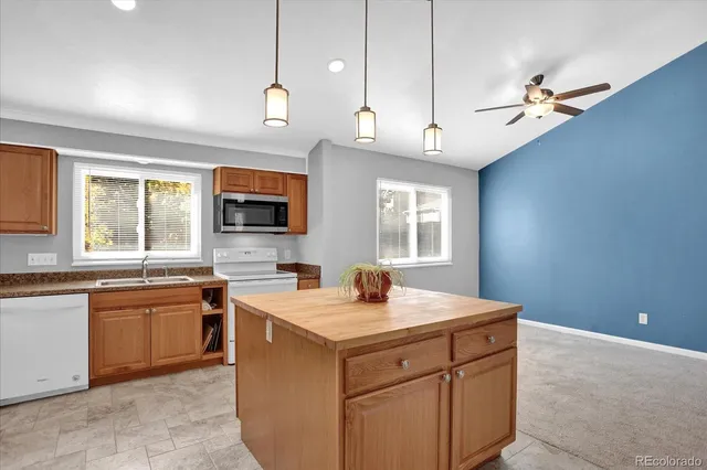 a kitchen with a sink a center island a stove cabinets and a window