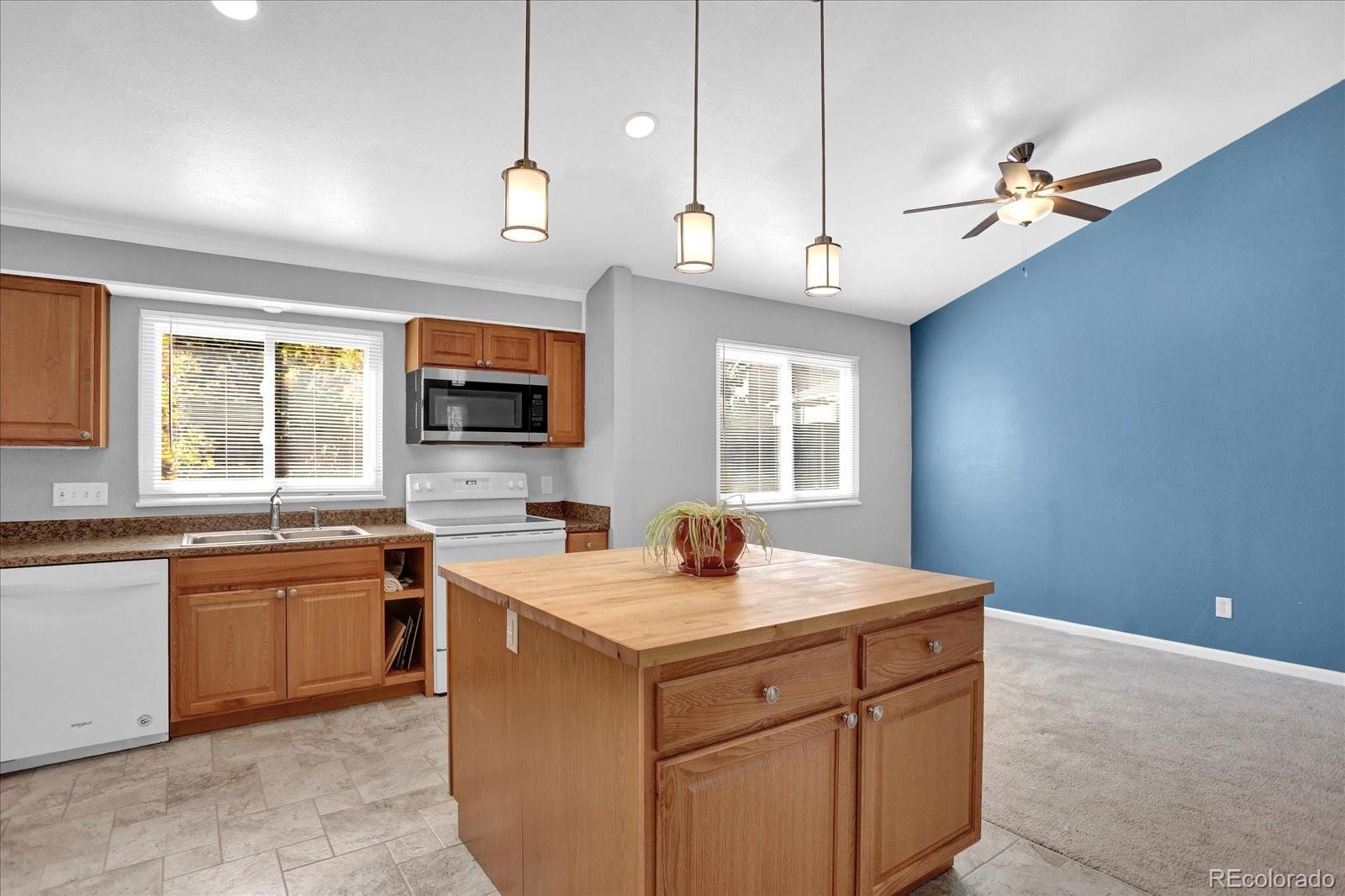 3754 South Walden Way Aurora, CO 80013 - Photo 11 of 32 a kitchen with a sink a center island a stove cabinets and a window
