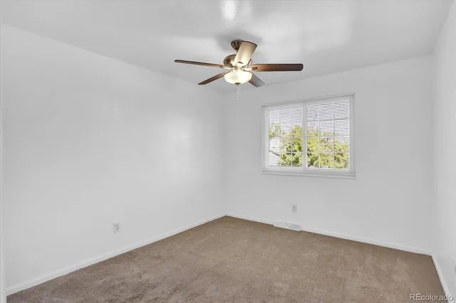 an empty room with a window and ceiling fan