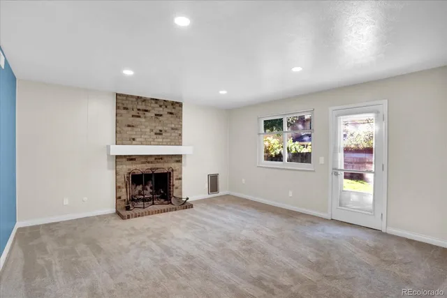 an empty room with windows and fireplace