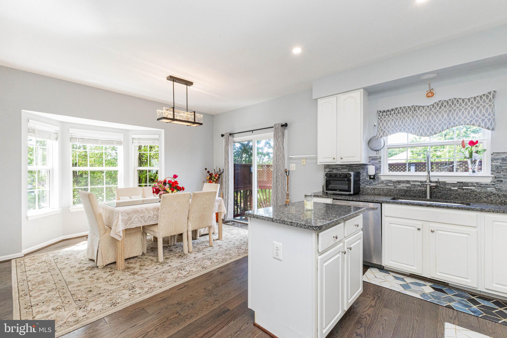 8226 Bates Road Lorton, VA 22079 - Photo 6 of 20 a large white kitchen with granite countertop a stove a sink a dining table and chairs