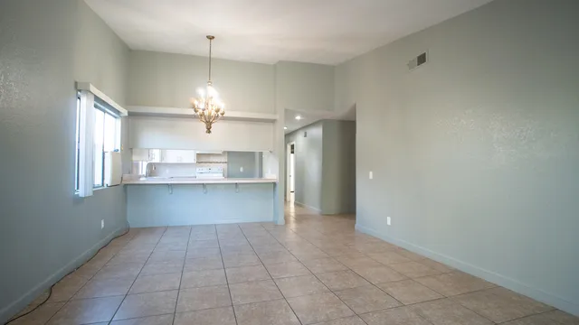 a view of kitchen with granite countertop cabinets a sink and a chandelier