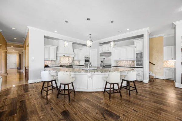a open kitchen with stainless steel appliances granite countertop a stove oven a dining table and chairs with wooden floor