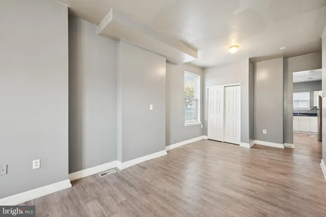 a view of an empty room with wooden floor and a bathroom