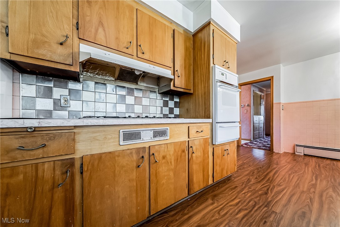 550 Cooper Foster Park Road Lorain, OH 44053 - Photo 12 of 50 Kitchen with light countertops, brown cabinets, dark wood-style flooring, oven, and under cabinet range hood