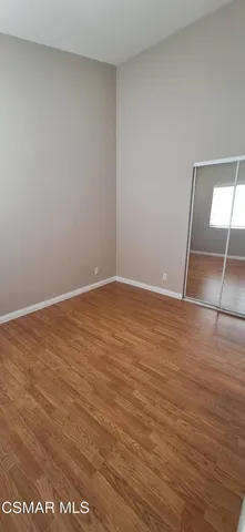 an empty room with wooden floor and mirror