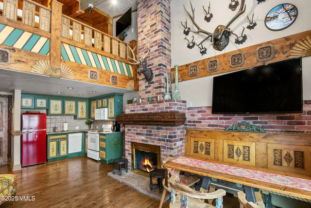 a living room with stainless steel appliances kitchen island a fireplace and a flat screen tv