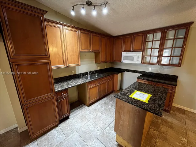 a kitchen with stainless steel appliances granite countertop a refrigerator a sink dishwasher a stove and a refrigerator