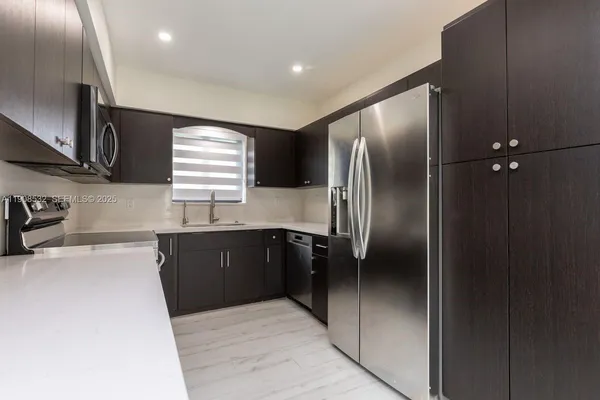 a kitchen with granite countertop stainless steel appliances cabinets a sink and a window