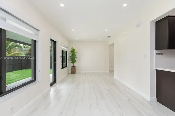 a view of an empty room with wooden floor and windows