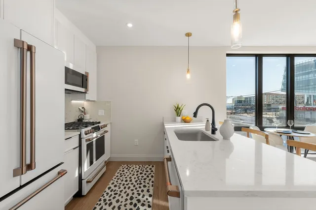 a kitchen with a stove a sink and a dining table with wooden floor
