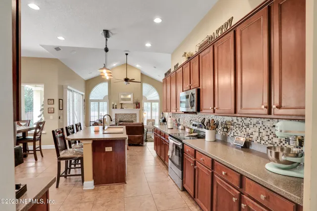 a kitchen with kitchen island granite countertop a table chairs sink and cabinets