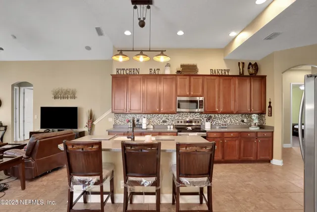 a living room with furniture a large window and stainless steel appliances