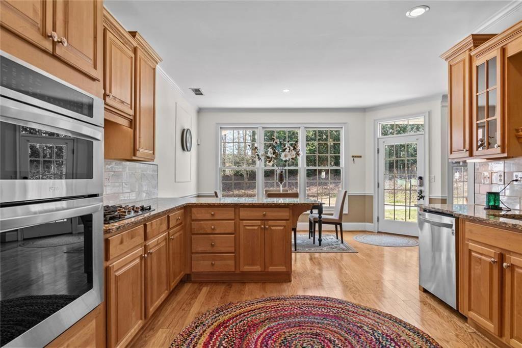 168 Jersey Road Oxford, GA 30054 - Photo 25 of 59 a kitchen with stainless steel appliances granite countertop a stove a sink dishwasher a microwave oven and a dining table with wooden floor