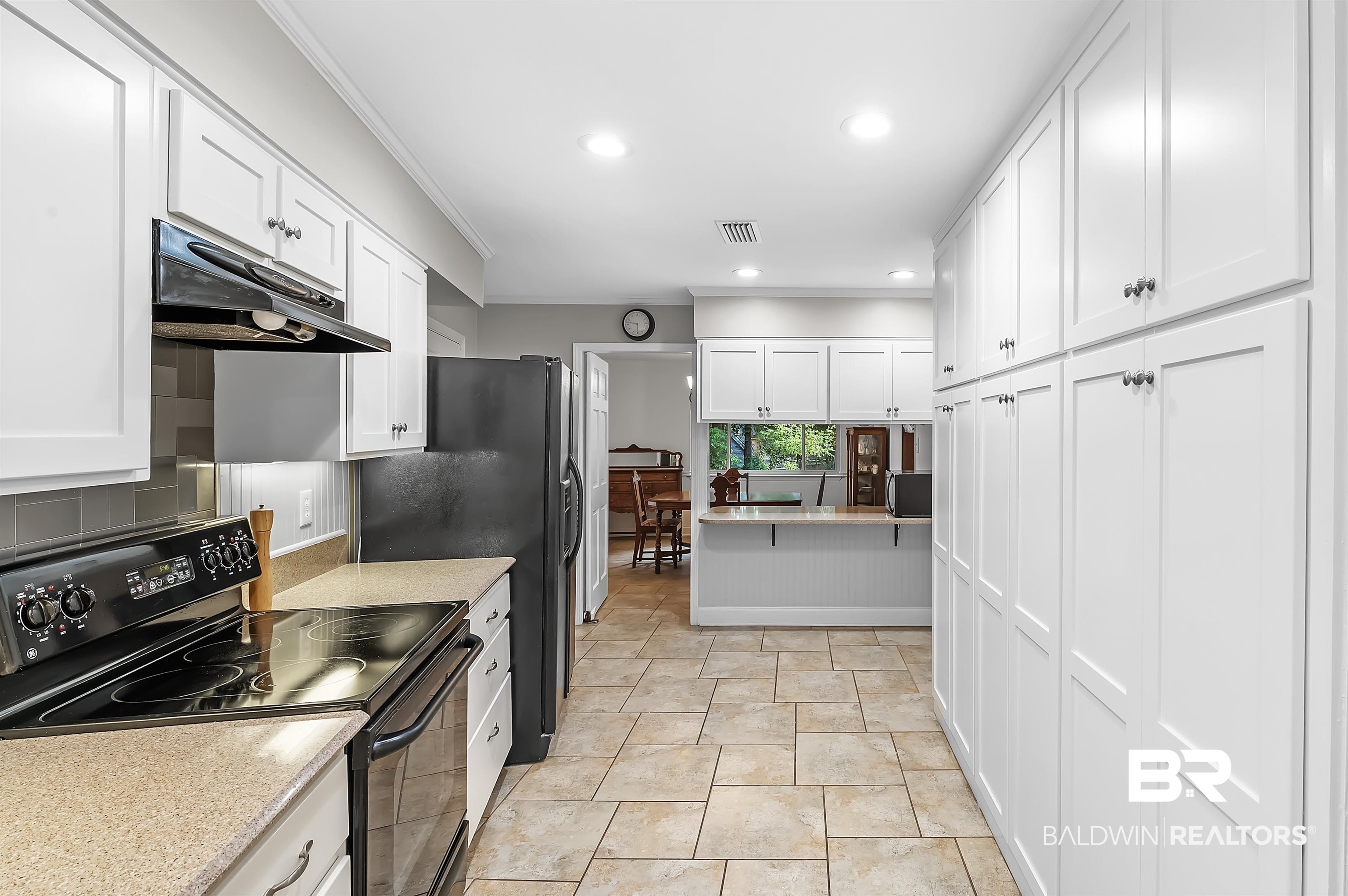 104 James Circle Daphne, AL 36526 - Photo 23 of 62 Kitchen featuring white cabinetry, light tile patterned floors, black / electric stove, and crown molding