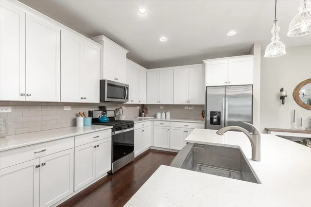 a kitchen with granite countertop a sink stainless steel appliances and white cabinets