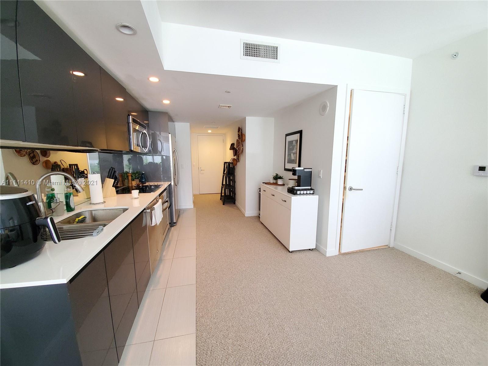 31 Southeast 6th Street, Unit 505 Miami, FL 33131 - Photo 14 of 71 a kitchen with kitchen island sink refrigerator and cabinets