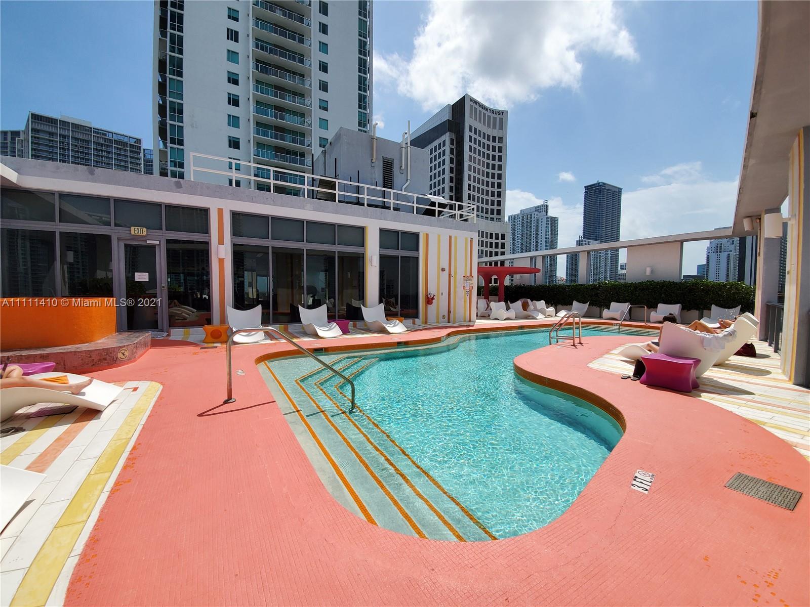 31 Southeast 6th Street, Unit 505 Miami, FL 33131 - Photo 39 of 71 a view of a swimming pool with a lounge chairs in front of building