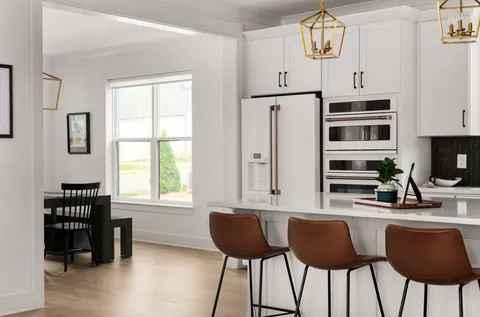a kitchen with stainless steel appliances a dining table chairs and a refrigerator