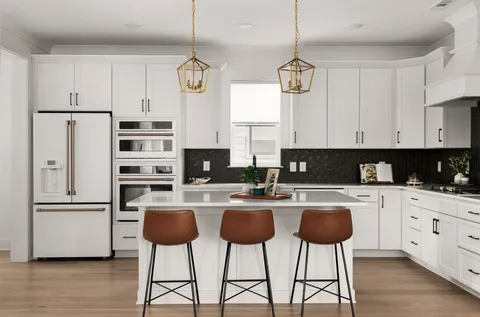 a kitchen with stainless steel appliances a stove a refrigerator and white cabinets with wooden floor