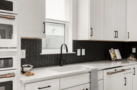 a kitchen with a sink dishwasher a stove and white cabinets