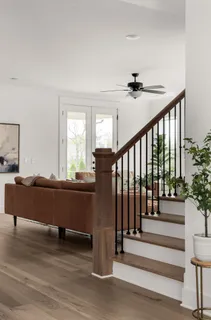 a living room with wooden floor and a ceiling fan