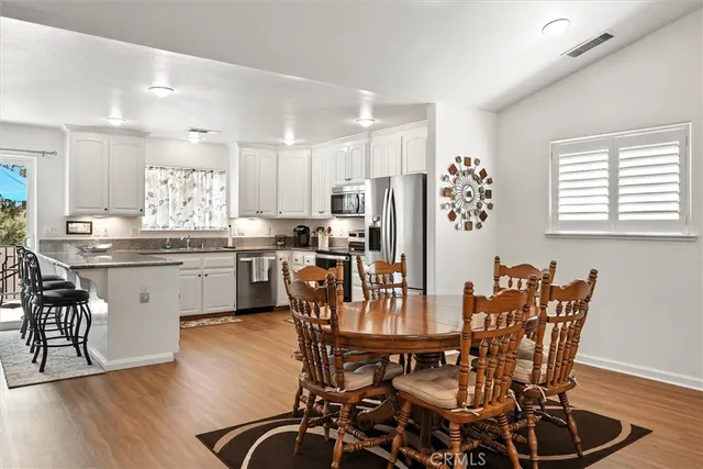 a kitchen with stainless steel appliances granite countertop a dining table chairs refrigerator and sink