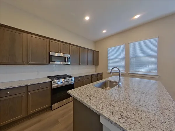 a kitchen with kitchen island granite countertop a sink cabinets and wooden floor