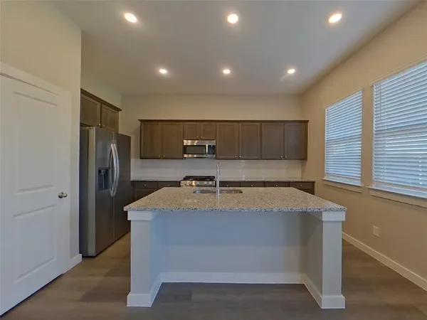 a large kitchen with stainless steel appliances a large counter top and a refrigerator